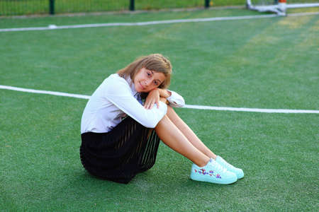 A girl in a school uniform with a racket in her hands on the football field.の写真素材