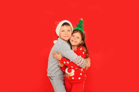 Boy and girl in New Years sweaters on a red background.の写真素材