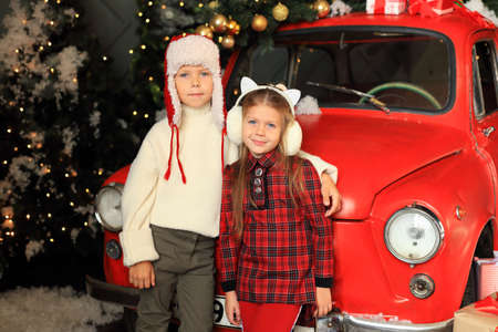 Children on the background of a red car with New Years gifts.の写真素材