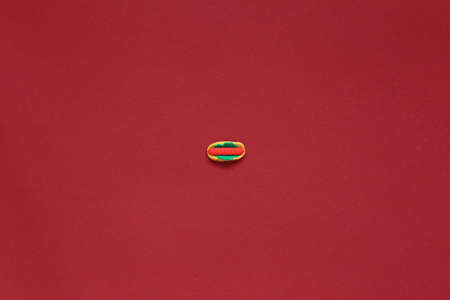 Small hot dog on a red background.