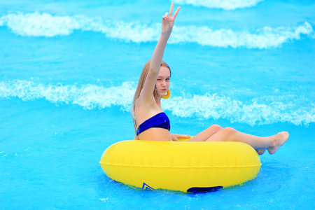 A beautiful young girl lies on an inflatable mattress in the summer water park.