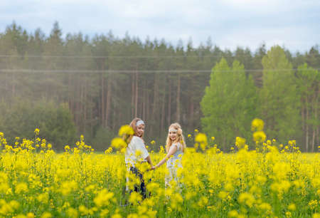 Two girls are walking along a blooming rapeseed field.の写真素材