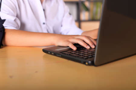 A young girl sits at a computer in the office. Schoolgirl in a laptop studies remotely. Office...