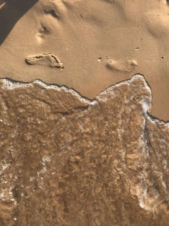 The sea washes away footprints in the sand. Footprint in the sand on the beach in summer.