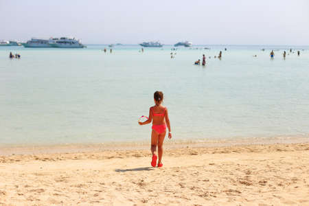 The child is resting in the summer on the sea. A tanned girl goes to the sea. Summer holiday with a child on the seaの写真素材
