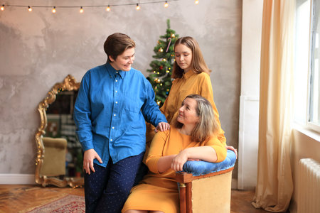 three women joyfully gathered around a beautifully adorned Christmas tree. Surrounded by twinkling...