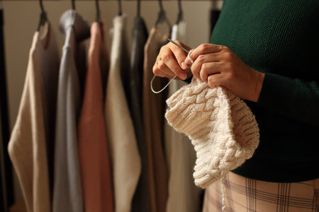 a pair of hands skillfully knitting a vibrant piece using light yarn and needles, set against a...