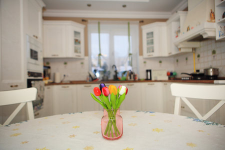 a solitary vase filled with vibrant flowers, gracefully standing on a table against the backdrop of a bright white kitchenの写真素材