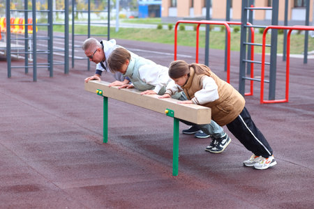 Two children are actively engaged in sports alongside their coach on a vibrant outdoor sports field....