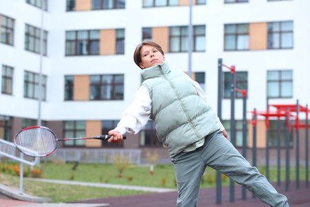 A teenager enthusiastically plays badminton on an outdoor sports playground, enjoying the thrill of the game during her weekend. Her focus and determination highlight the joy of physical activityの写真素材