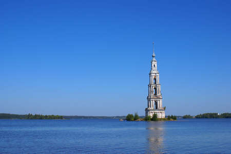 High belltower in the middle of the wide riverの写真素材