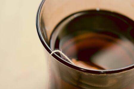 A rope with a tea bag on the edge of a transparent cup with tea. Tea mood. magco defocused cup of...