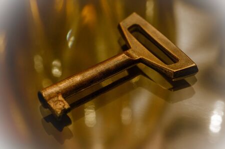 Golden key close-up on a glass surface. The key to all the doors. Decorative key in decorative...