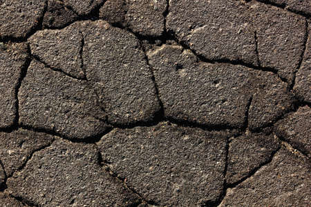 Background old asphalt with deep cracks close-up. Texture of old asphalt in hard sunlightの写真素材