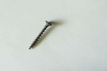 The self-tapping screw lies on a light embossed background with side lighting