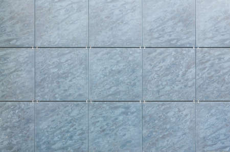 background of light blue facade tiles under soft light. facade tile texture close-up