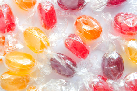 multicolored lollipops candies in a transparent package are scattered on a light backgroundの写真素材