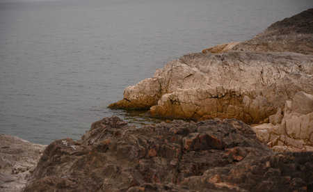 A rocky shore next to a gray sea. Gloomy view, hopelessness.