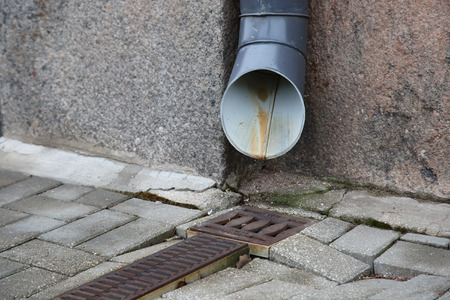 Water drain near wall on the street of cityの写真素材
