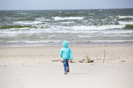 Girl running on the sand beach near the seaの写真素材