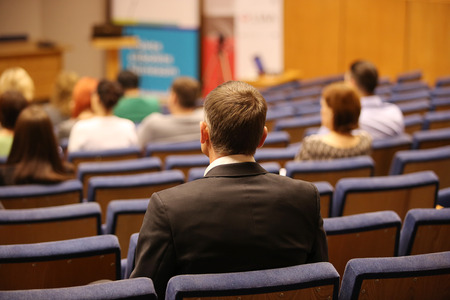 People at the conference hall. Rear view. Man in black suit