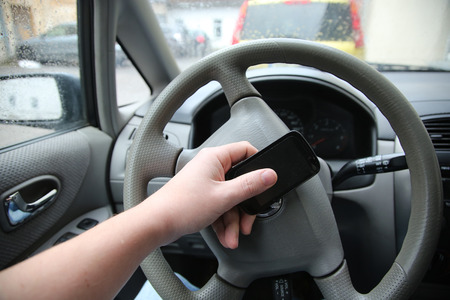 man sitting in the car and holding a touch phone with balck screen