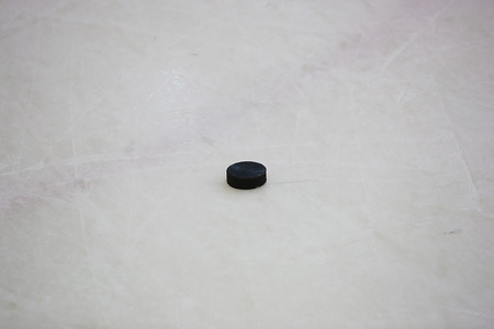 The black hockey puck on ice rinkの写真素材