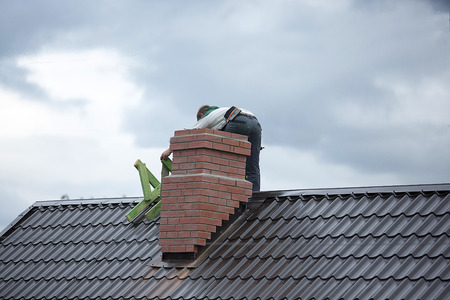 Worker on the roof repairs brick chimneyの写真素材