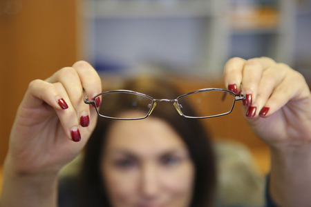 woman hands hold eyeglasses in front of herの写真素材