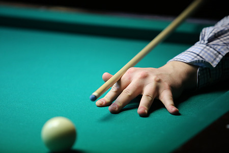 Billiard player . hand with cue prepare hit a ball