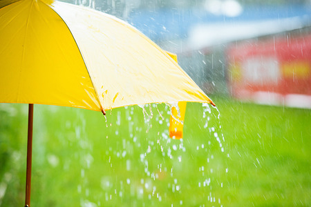 Rain drops falling from a yellow umbrella concept for bad weatherの写真素材