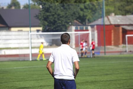 Football coach watching the match at sunny time