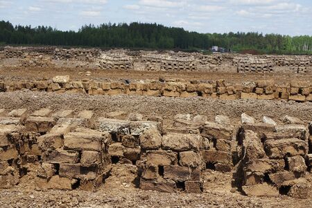 Pile of stacked bog peat turf briquette cuttings left drying in the field