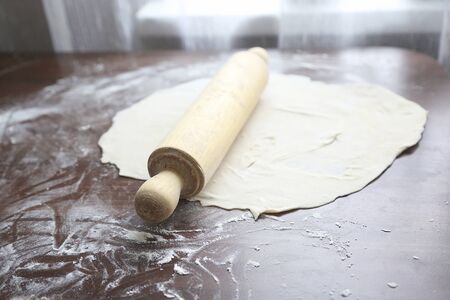 fresh unbaked dough with rolling pin on wooden board