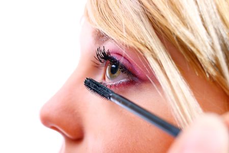 Pretty woman applying make up on a white backgroundの写真素材