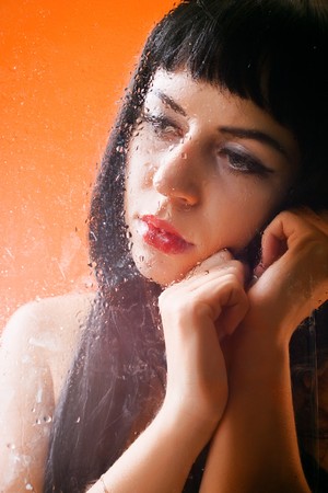 Woman behind glass with rain dropsの写真素材