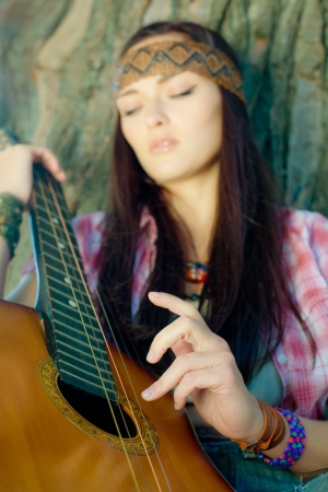 Beautiful hippie girl with guitar. Focus on hand.の写真素材
