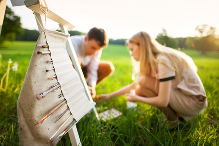 Young couple painting on an easel in a fieldの写真素材