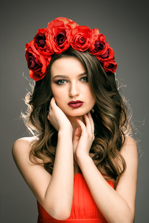 Pretty woman with wreath of red roseの写真素材