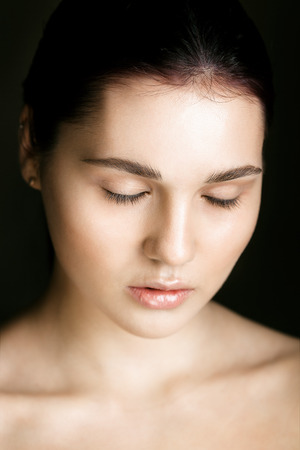 Beautiful young woman in the nude with eyes closed over black backgroundの写真素材