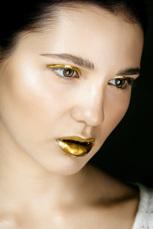 Attractive young woman with unique golden makeup.の写真素材