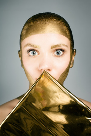 Woman with gold face make up fashion. Gold art fashion make up.の写真素材