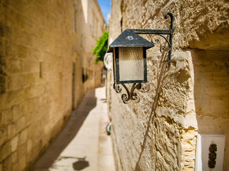 Old black lantern on the stone wall. Former capital of island Malta - Mdina.の写真素材