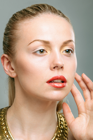 Beautiful woman wearing golden jewelry. Deep retouch.の写真素材