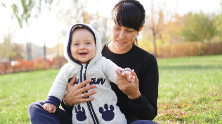 Cute cheerful child with smiling mother on the lawn in the garden