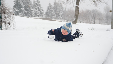 Little boy having fun floundering in the snow in winter parkの写真素材