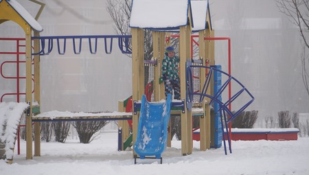 Little boy on the children playground in winter time