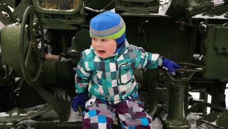 Brave child playing at the gun control panel in winter park withの写真素材