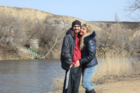 young lovely couple resting on beach, handsome man and beautiful woman smiling and kissing on a coast river, happy family conceptの写真素材