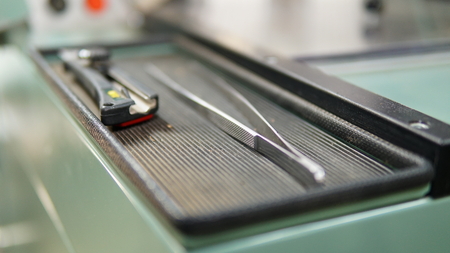 Steel tweezer and office cutting knife on the trayの写真素材